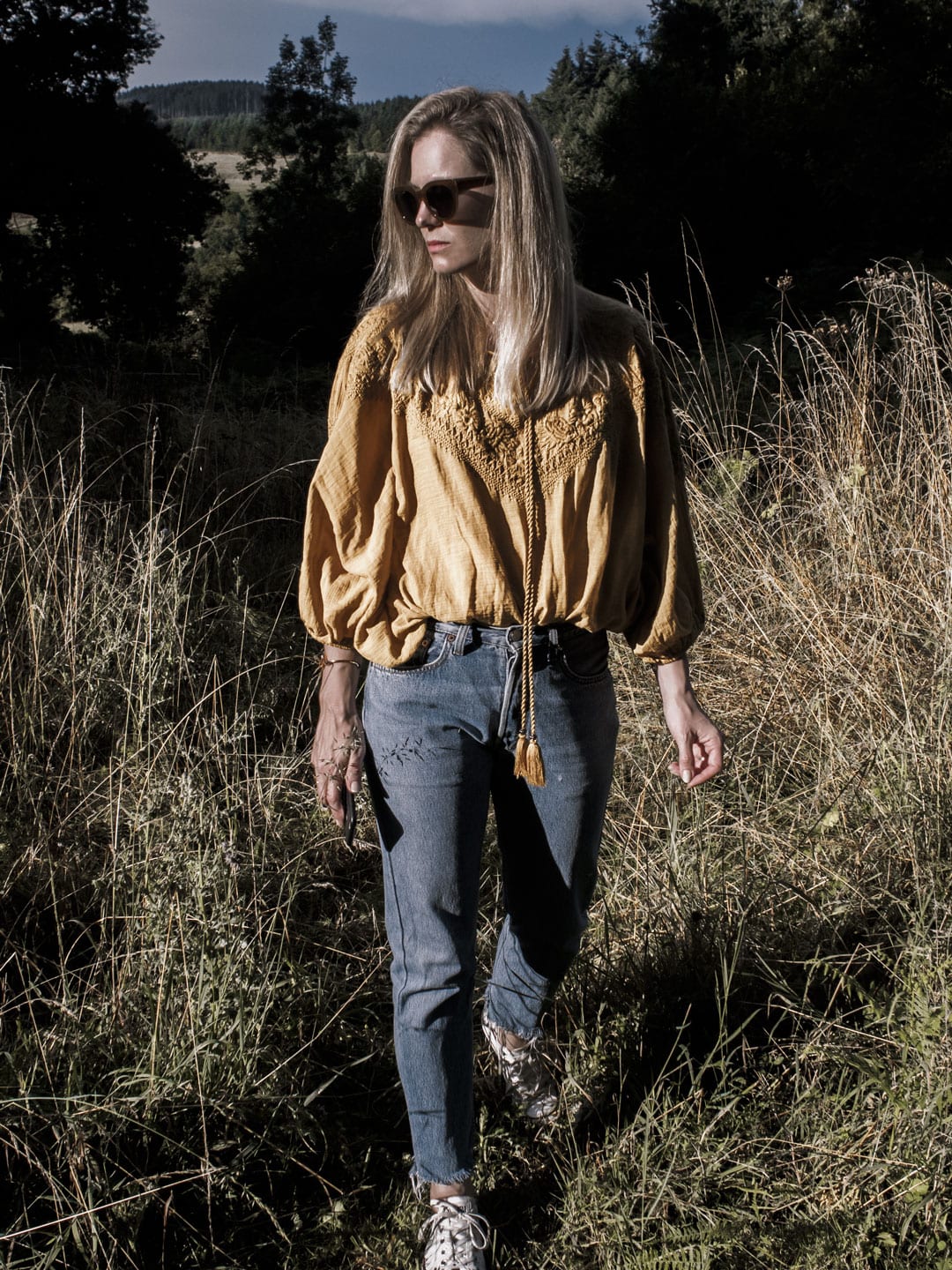 Photo of woman wearing yellow boho peasant top, Levi 501s & Converse plimsolls in French field